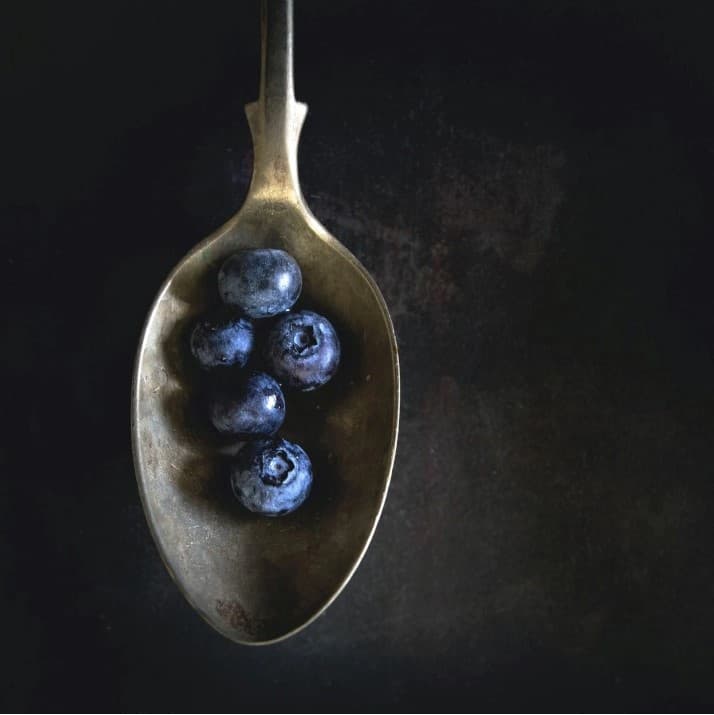 Blueberries in a spoon, fresh and vibrant. A delightful treat, perfect for a healthy snack. Stay current with these juicy blueberries.